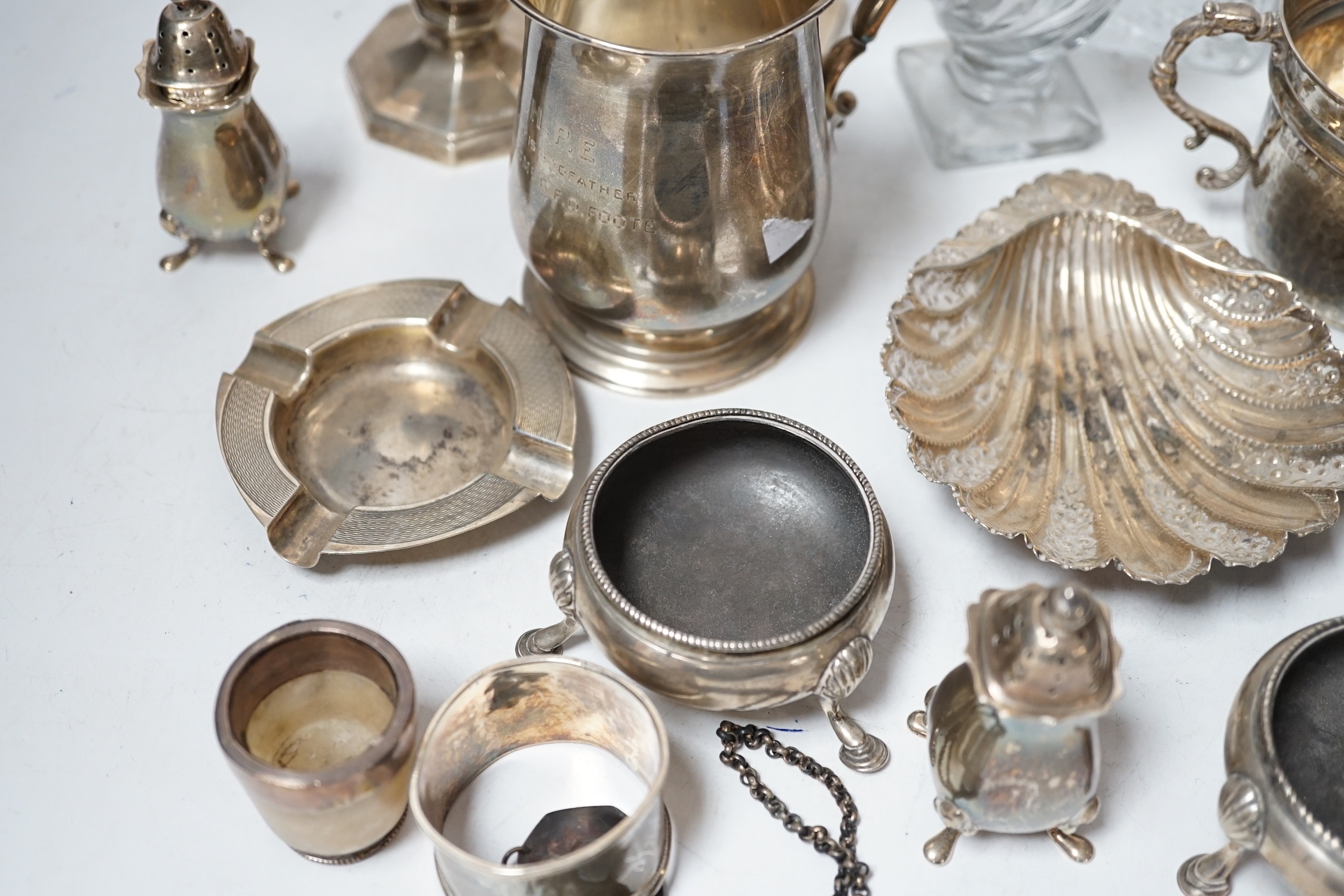 Assorted small silver including a christening mug, a planished porringer, pair of George V sugar casters, butter shell, ashtray, two mounted glass posy vases, four condiments, four napkin rings, a mounted glass cruet bot